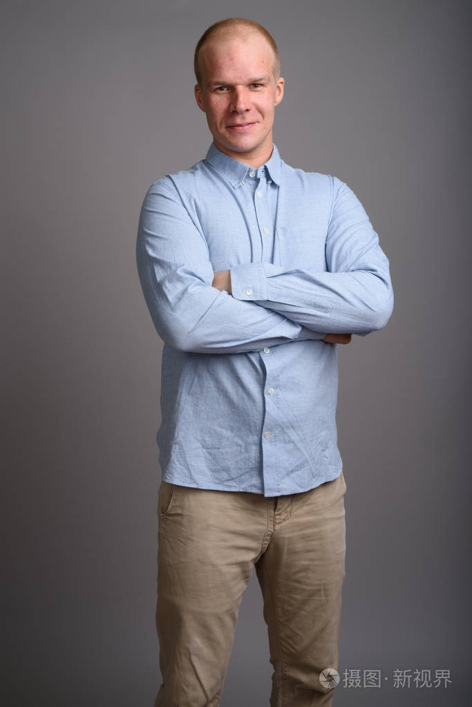 光头商人穿着蓝色衬衫反对灰色背景