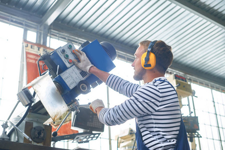 工业车间年轻厂工操作机组的侧面图照片