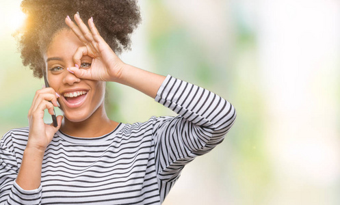 年轻的美国黑人妇女谈论在手机上的独立背景与快乐的脸微笑做 ok 标志与手在眼睛看通过手指