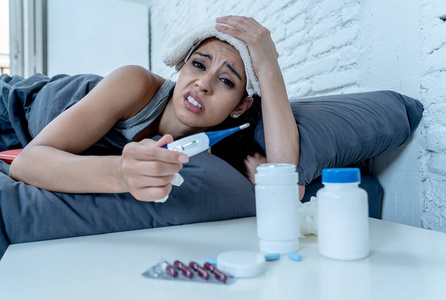 生病的有吸引力的女人躺在床上感觉不适与头痛疼痛鼻子高温感觉疲劳和不安不能够去工作在医疗保健概念