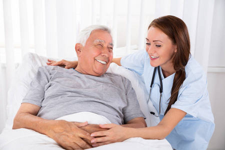 护士看着快乐的男性病人躺在床上的诊所