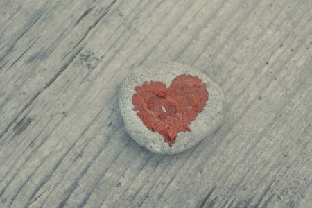 粉红色的心在一块石头上涂上口红在木板的背景上