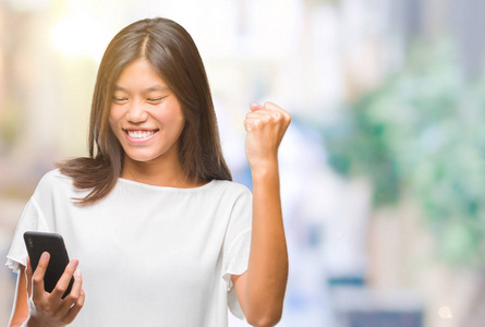 年轻的亚洲妇女发短信使用智能手机在孤立的背景尖叫自豪和庆祝胜利和成功非常兴奋, 欢呼的情绪