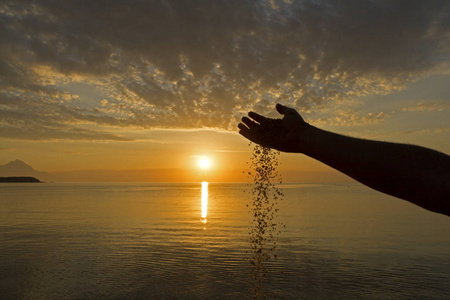 倒计时器生命时间流逝的概念.人手在日出背景上倒沙照片
