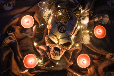 Helloween 头骨在黑暗中用花环。温暖的光和褐色的蜡烛