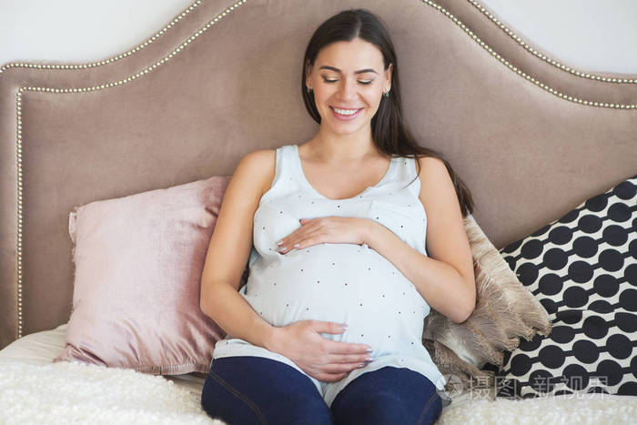 怀孕妇女在室内坐在床上