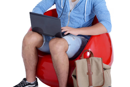 年轻男子坐在红色凳使用笔记本电脑关闭