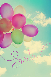 五颜六色的大气球与刻字微笑在天空背景照片