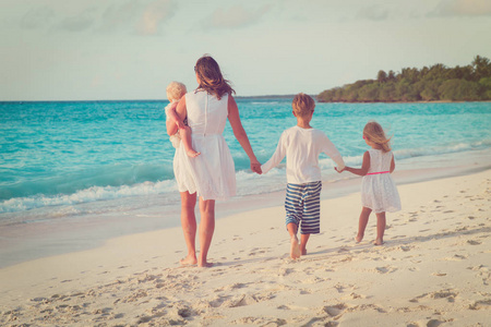 母亲带着三个孩子走在海滩上