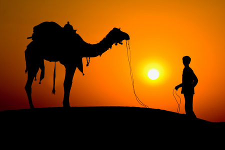 一个男人和一个在沙漠里斋沙默尔印度骆驼日落时的剪影