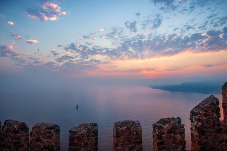 山上的堡垒墙上的夕阳在海面上的阳光透过云层。假日度假旅游海景色调景观宽角