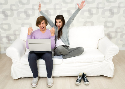 年轻的夫妇在沙发上使用便携式计算机