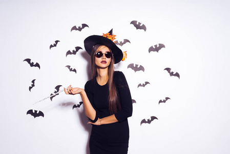宽万圣节晚会艺术设计万圣节女巫在一个可怕的黑色帽子微笑。背景下的一堆蝙蝠