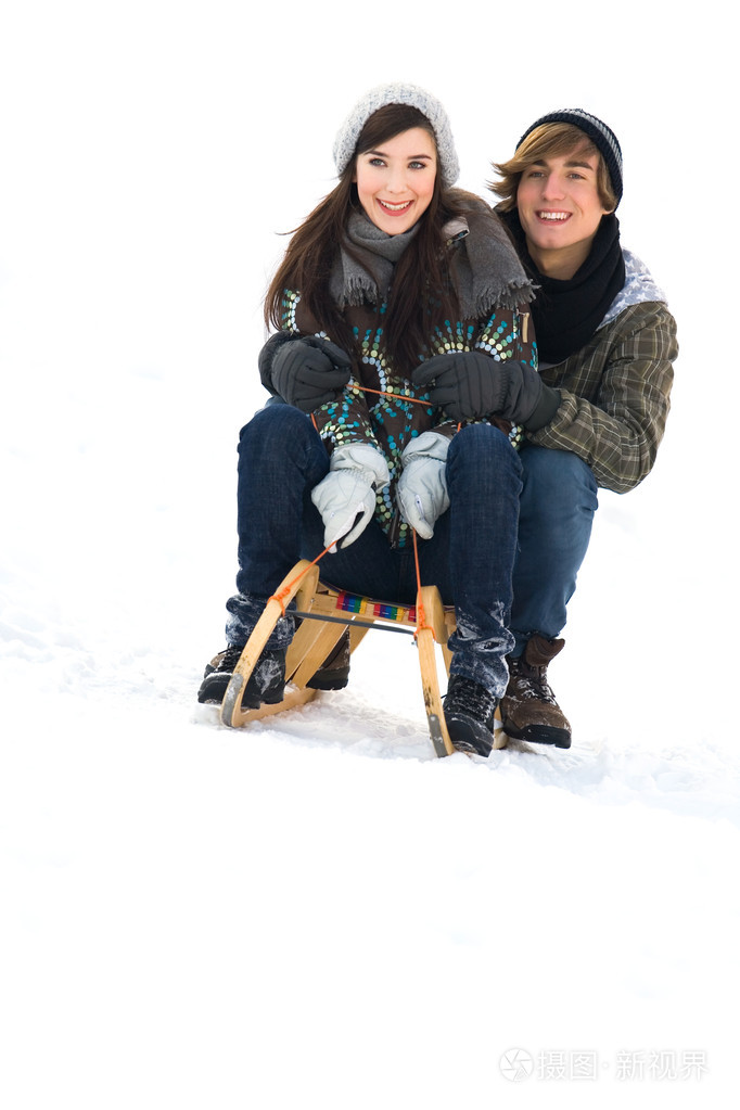 年轻的夫妇在雪橇在雪中上