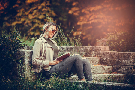 年轻美丽的妇女阅读一本书和享受自然