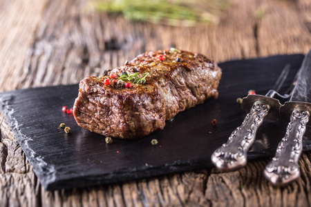 牛肉牛排。烤的牛肉牛排配盐胡椒百里香仿古木制的桌子上