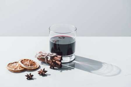 在白色桌面上的玻璃, 肉桂棒和干桔子的热葡萄酒