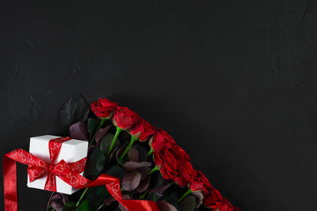 顶部查看新鲜红玫瑰花和礼品盒在黑色甲板上与 e