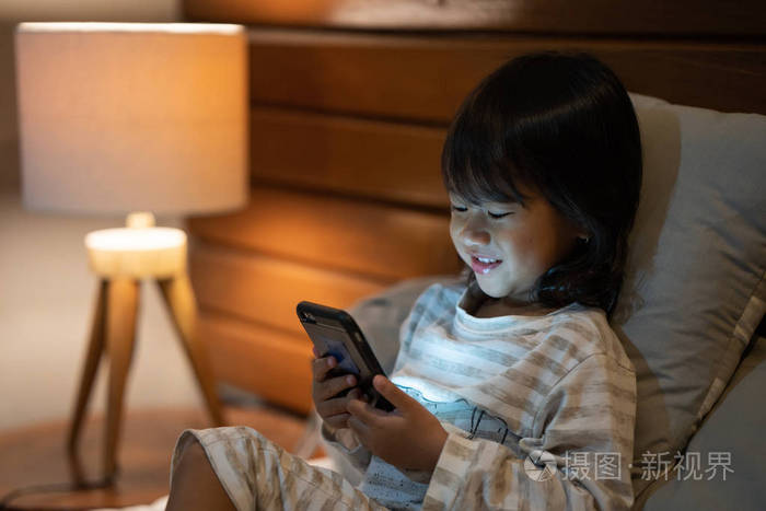 纵向小女孩喜欢看视频与智能手机照片-正版商用图片06970k-摄图新视界