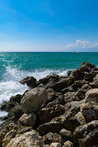 海滩上清澈的海水中的大石头。浅波纹水面。海滩上的大石头和石头. 日光概念背景下的松弛景观观点。游艇之遥