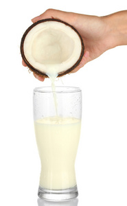 椰子牛奶倒入玻璃白色背景上的女人的手