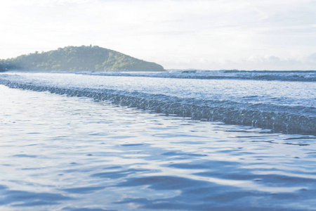 沙滩上的蓝色海洋的柔和波浪。背景沙子和海浪在海滩背景。为文本和其他内容在底部放置空格