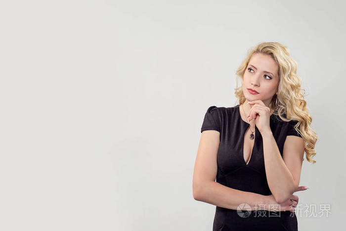 优雅的金发女人抚摸下巴, 而在灰色的背景思考看着