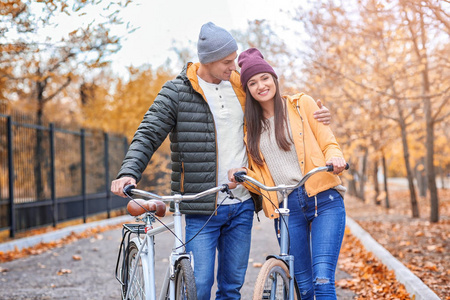 年轻夫妇步行与自行车在公园