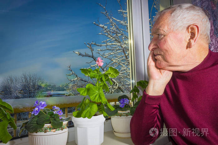 老孤独的人坐在他家的窗户附近