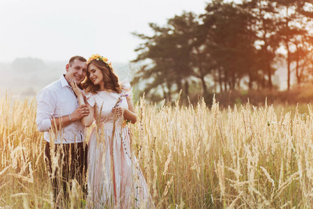 快乐的女人与她的丈夫在秋季在高高的草地在日落的季节