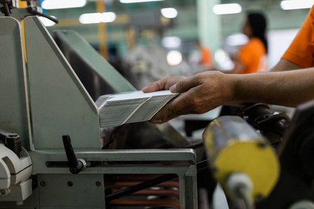 工人在看图纸在现代印刷厂中关闭工人手准备纸箱印刷的镜头照片