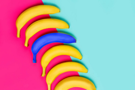 亮蓝色香蕉在黄色果子在粉红色和柔和的蓝色背景, 顶部看法