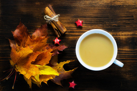 一杯热咖啡与牛奶和香料和秋天的叶子在木桌上。一杯卡布奇诺咖啡, 枫树叶
