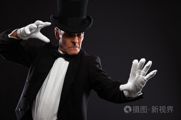 魔术师使神秘的手势戴着帽子和黑色西装