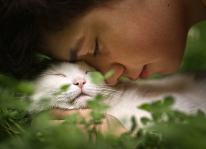 少年男孩与猫亲吻拥抱在绿色夏天草关闭相片
