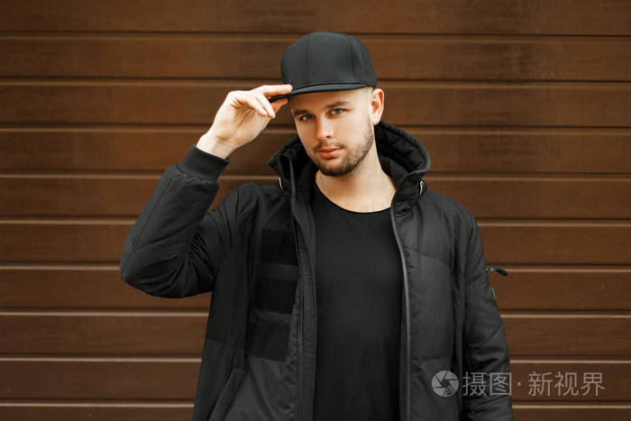 英俊的年轻男子在一个黑色的时尚棒球帽和黑色冬季夹