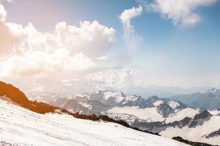 深蓝色的天空，云在山的多岩石的山峰上覆盖着冰川和积雪