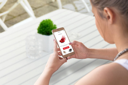 网上购物的妇女与智能手机.寻找女鞋.背景咖啡店桌照片