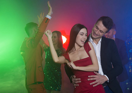 一群年轻快乐的朋友在聚会上跳舞。男人和女人在镜头前的前台跳舞