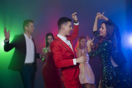 一群年轻快乐的朋友在聚会上跳舞。男人和女人在镜头前的前台跳舞