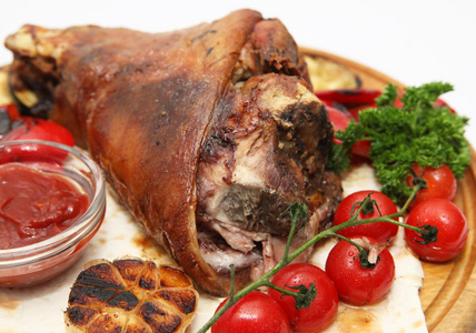 猪肉小腿与蜂蜜釉的蔬菜被隔绝在白色木制板上