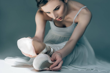 美丽的芭蕾舞演员在白色的礼服伸展腿在工作室