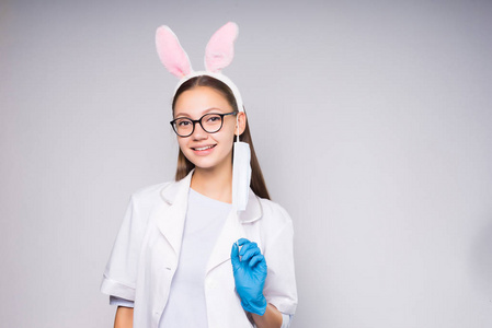 一个年轻有趣的女孩与 rim 在形式的兔耳朵和眼镜，微笑着，戴着蓝色医用手套