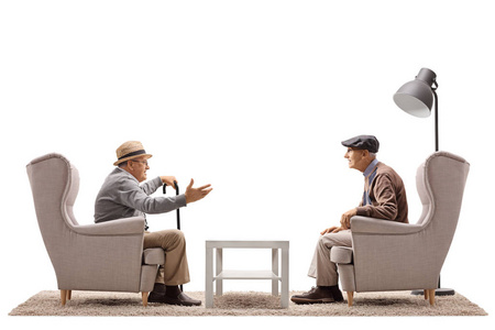 坐在扶手椅上交谈的年长男子照片