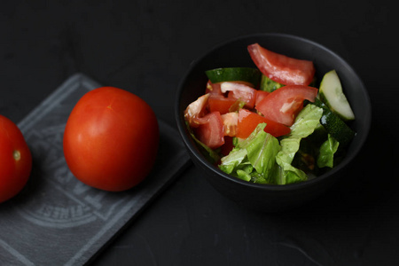 两个西红柿在一个灰色的陶瓷雨与碗沙拉美味的食物为您的食谱在黑暗的背景