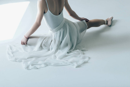 优雅的芭蕾舞演员坐在白色礼服的裁剪视图