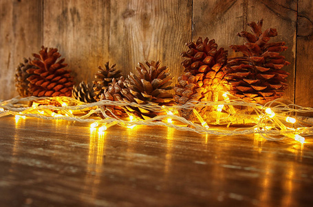 节日图像与圣诞金色花环灯和松果在木制的背景