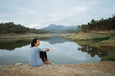 亚洲女人坐在一条河边