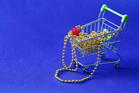 在蓝色背景下, 一朵小纸花躺在塑料珠子上, 金球的形式, 所有在商店的购物车