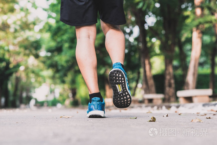 在公园的早晨跑步者脚的后面看法慢跑